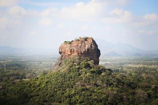View of the iconic Sigiriya Rock Fortress, surrounded by lush vegetation in Sri Lanka.