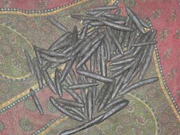 Dark, hand-rolled sticks of cannabis resin on a patterned cloth