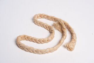 A length of pale plaited cord laid in loose loops on a white background, frayed at both ends